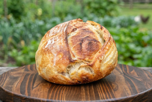 Golden croissant sourdough loaf with a flaky, scored crust on a wooden board